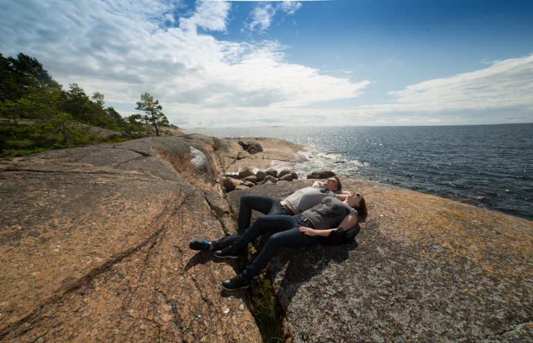 Kaksi ihmistä makailee Nuokkojen kalliolla