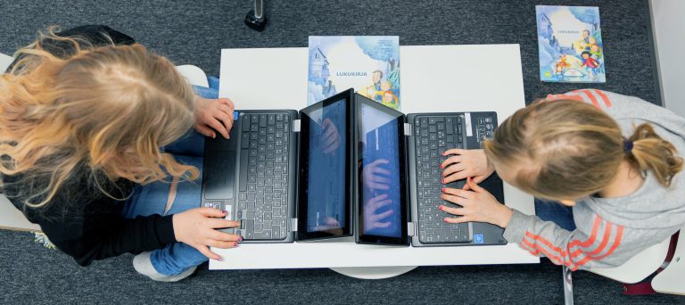 kaksi tyttöä istuu vastakkain ja opiskelevat kannettavien tietokoneiden kanssa